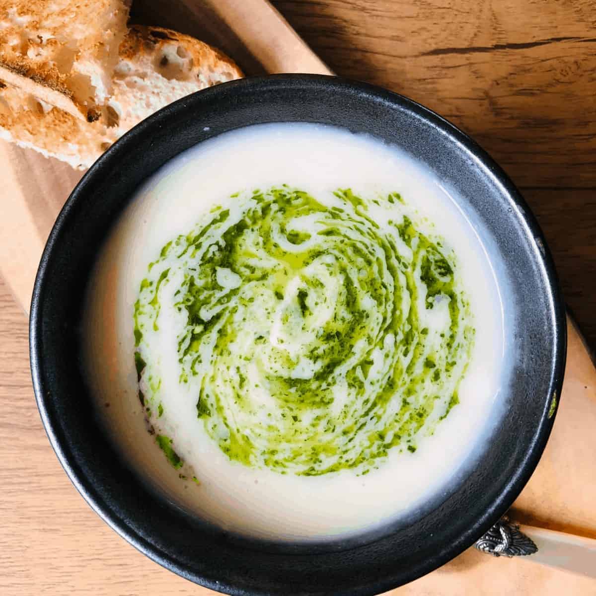 Bowl of cauliflower soup with a pesto garnish.