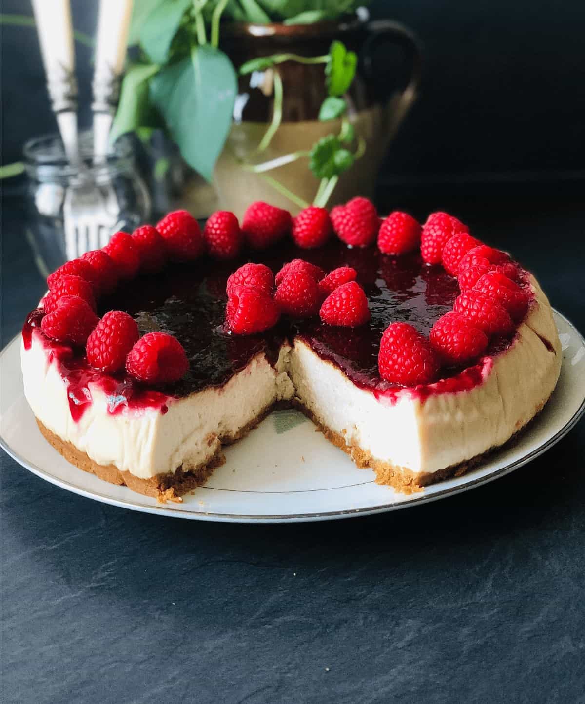 Whole baked vegan cheesecake on a plate with a slice removed.