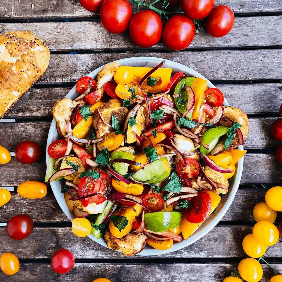 A plate of Panzanella salad on a slatted wooden table.