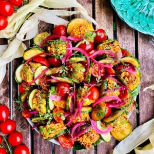 A plate of grilled sweetcorn salad with cucumber and tomato and pickled onion.