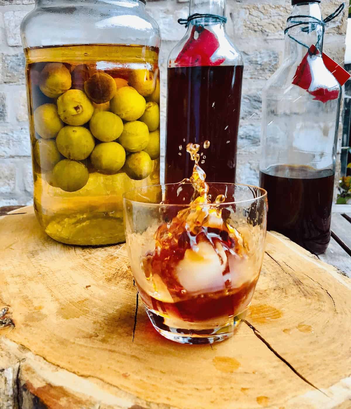 A glass of umeshu plum wine with an ice cube splashing into it.
