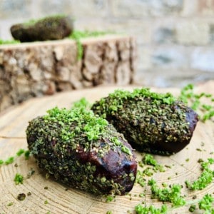 Close up of two stuffed dates sprinkled with nettle seeds. 