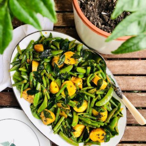 Oval shaped platter of potato and greens salad with an Indian pickle dressing.