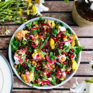 A plate of roasted cauliflower salad, tandoori style sitting on a slatted wooden table. 