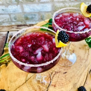 Two margarita glasses containing wild blackberry margarita cocktail. 