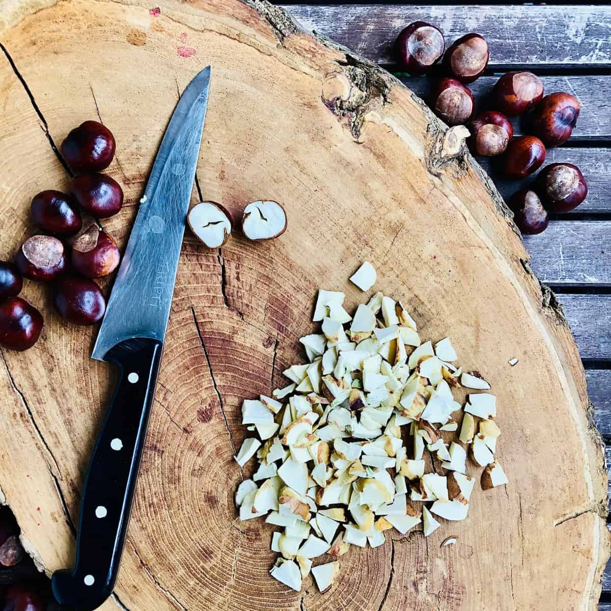 Chopped conkers with a knife on a tree trunk platter.