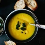 A bowl of curried parsnip soup with a curry lead and mustard seed tadka garnish.