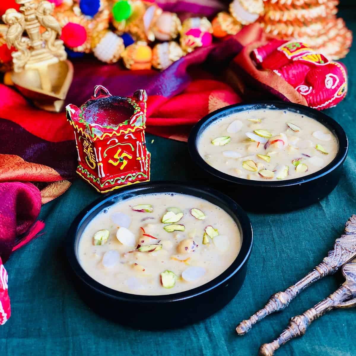 Two shallow dishes of makhana keer sat on a dark green cloth. 