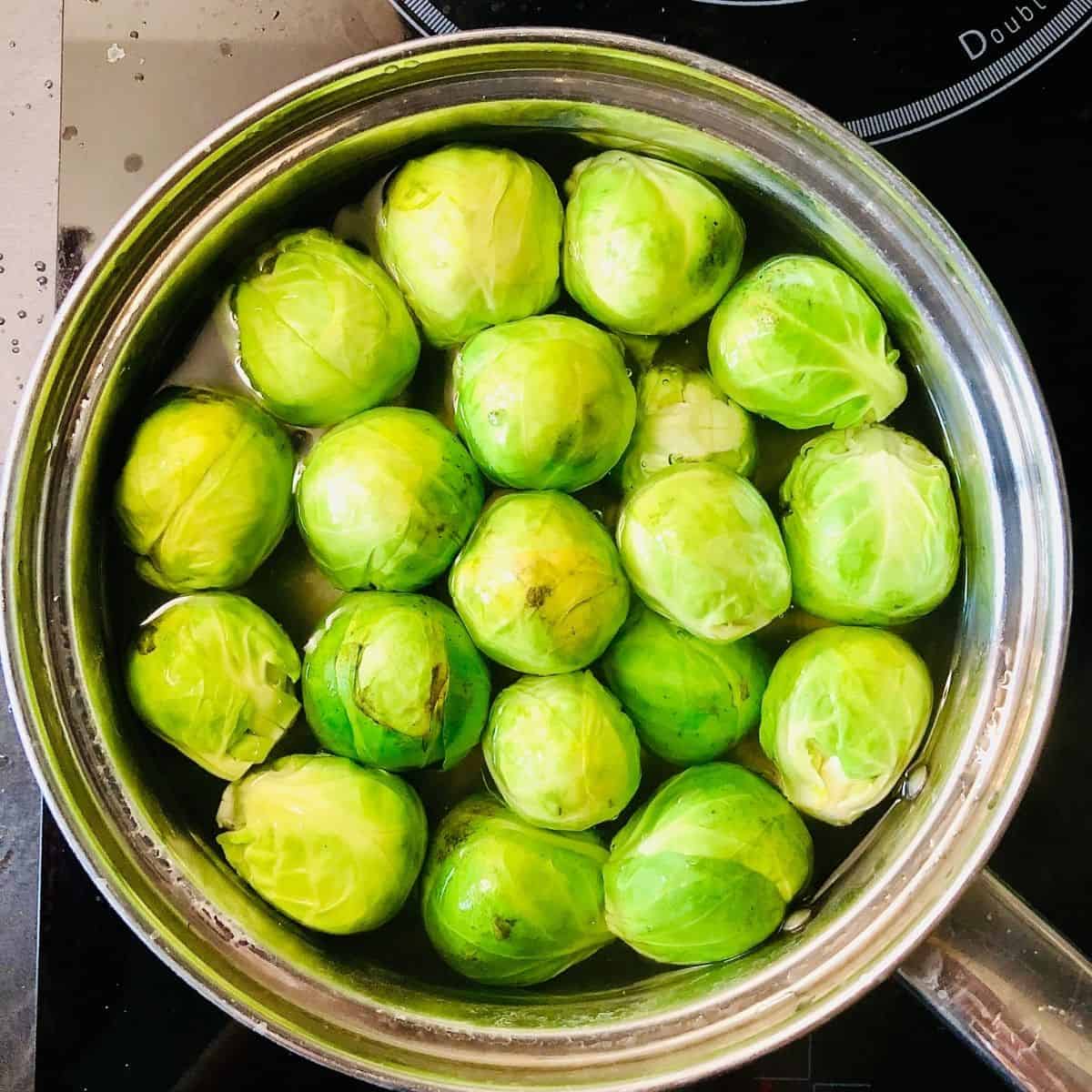 A pan containing brussel sprouts in water 