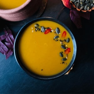 A bowl of roast pumpkin soup garnished with a seed mix