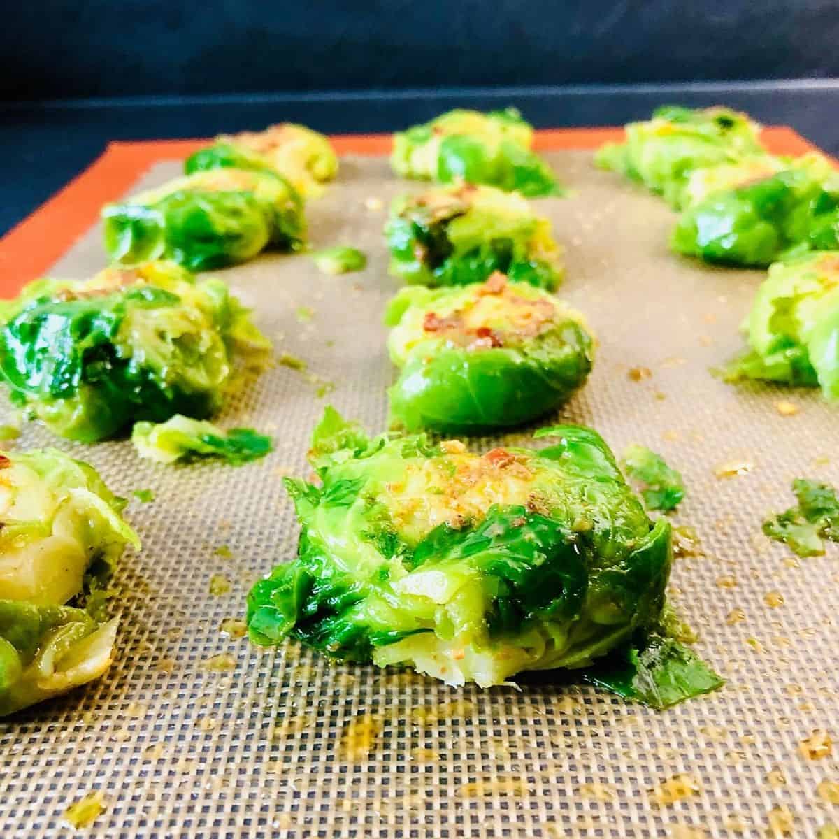 Rows of smashed brussel sprouts on a silicone mat