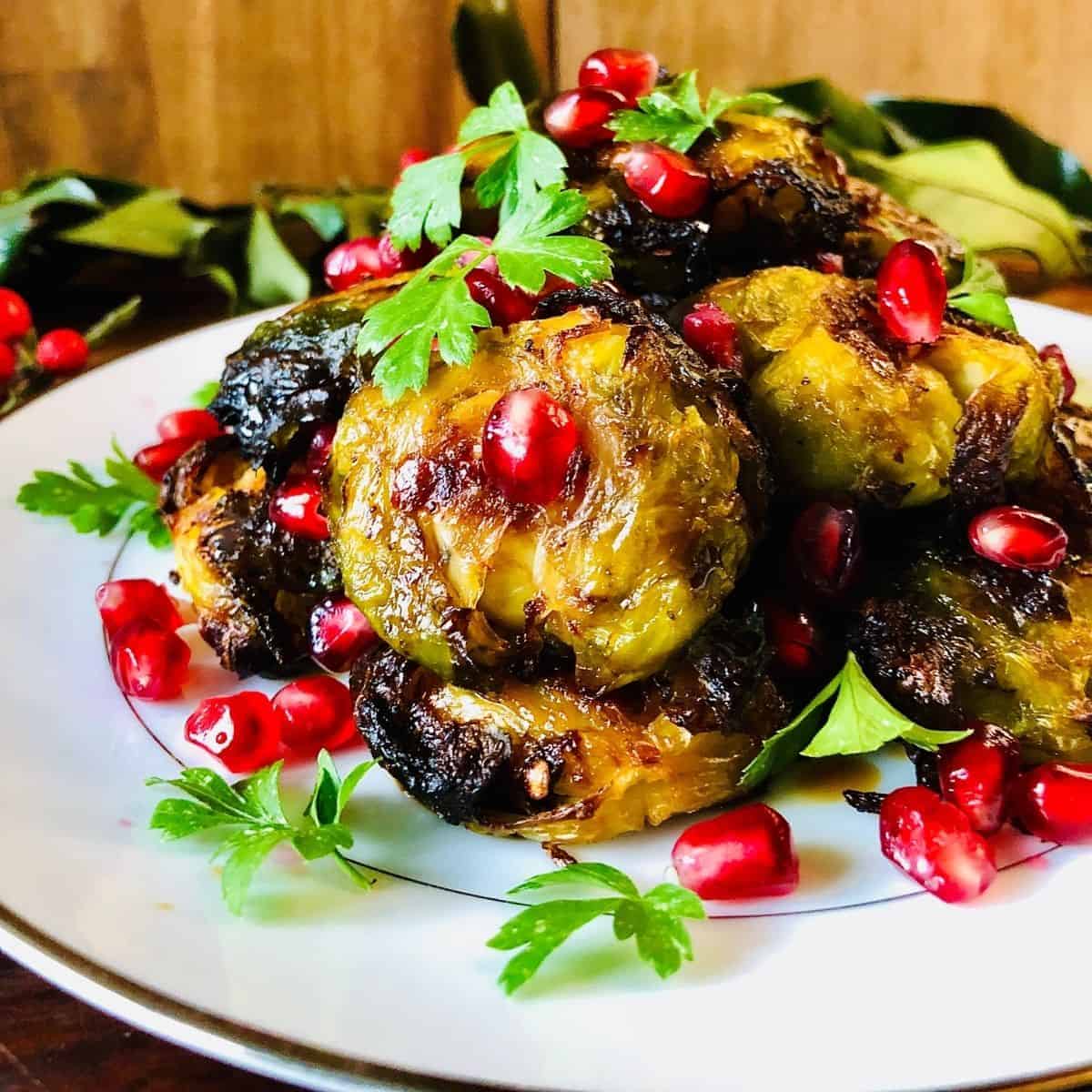 Smashed brussel sprouts arranged on a plate, garnished with Pomegranate seeds and parsley