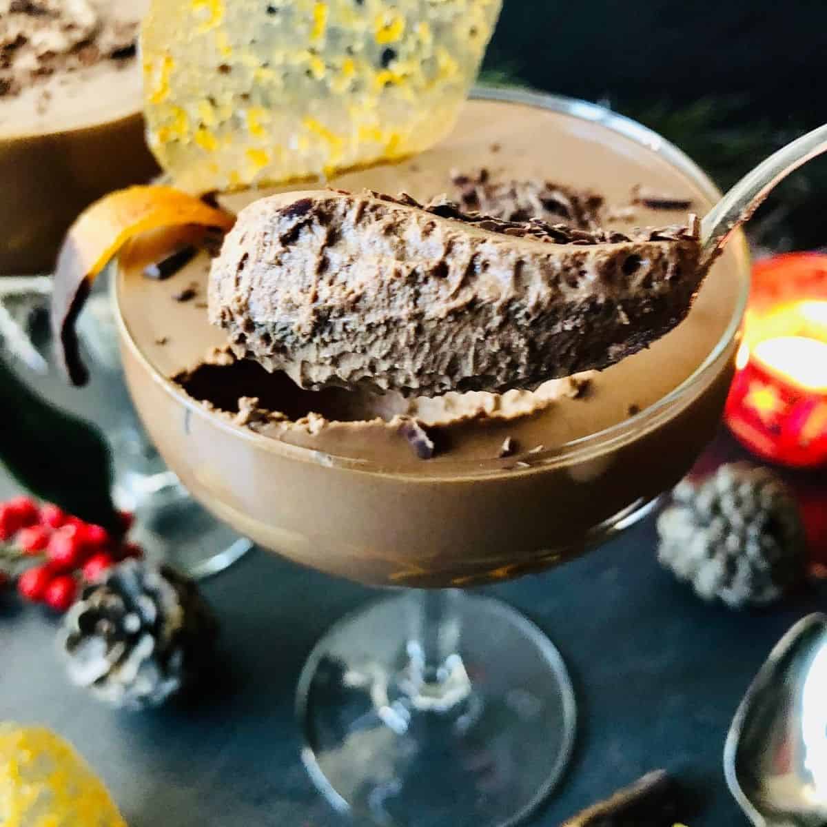 Scoop of vegan Chocolate mousse on a teaspoon held above champagne glass containing the vegan chocolate mousse 