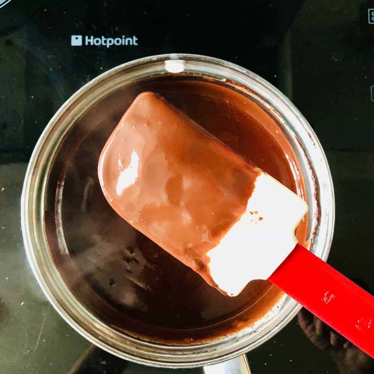 A saucepan containing cream, sugar and melted chocolate mix. 