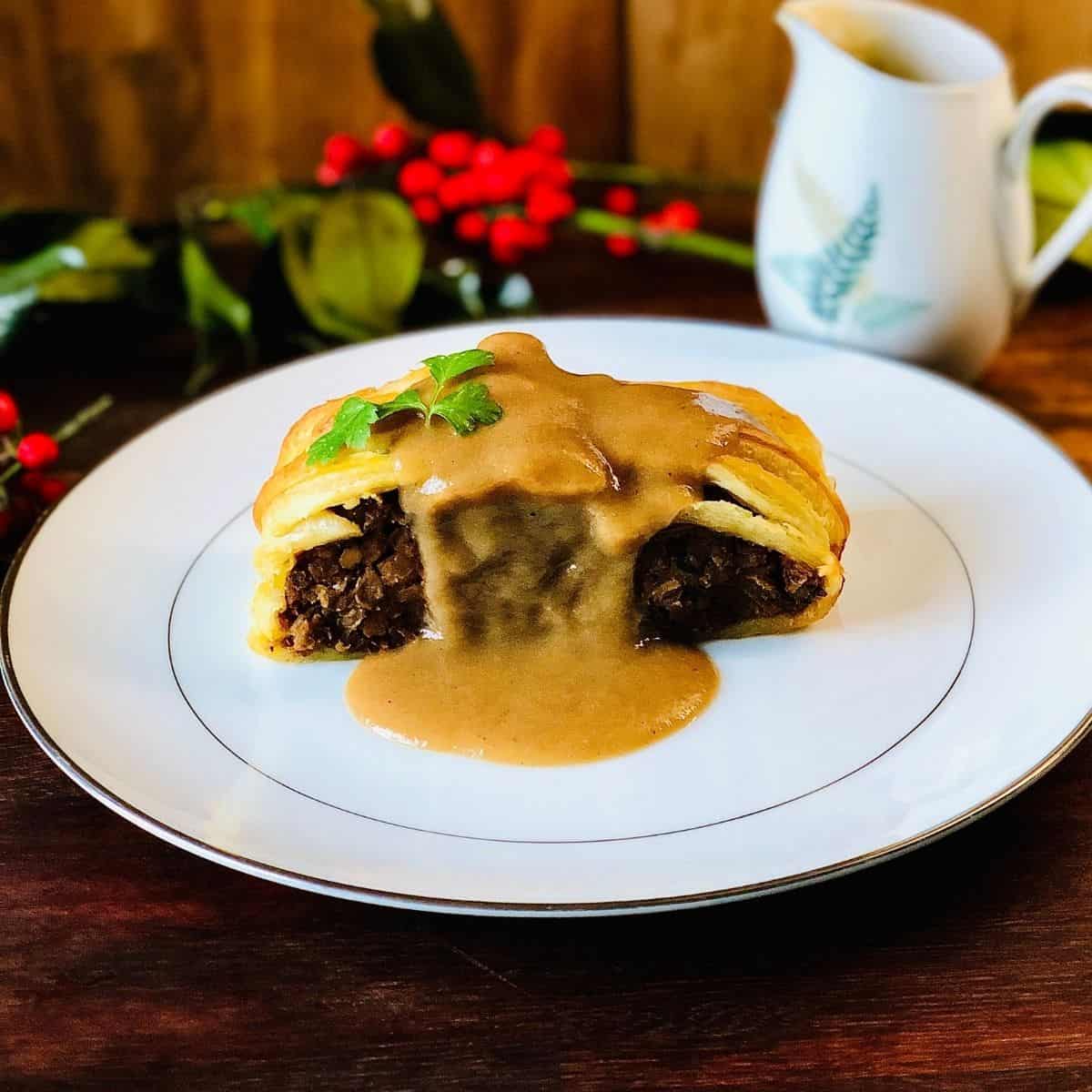 Close up photograph of a vegan wellington on a plate covered in vegan gravy