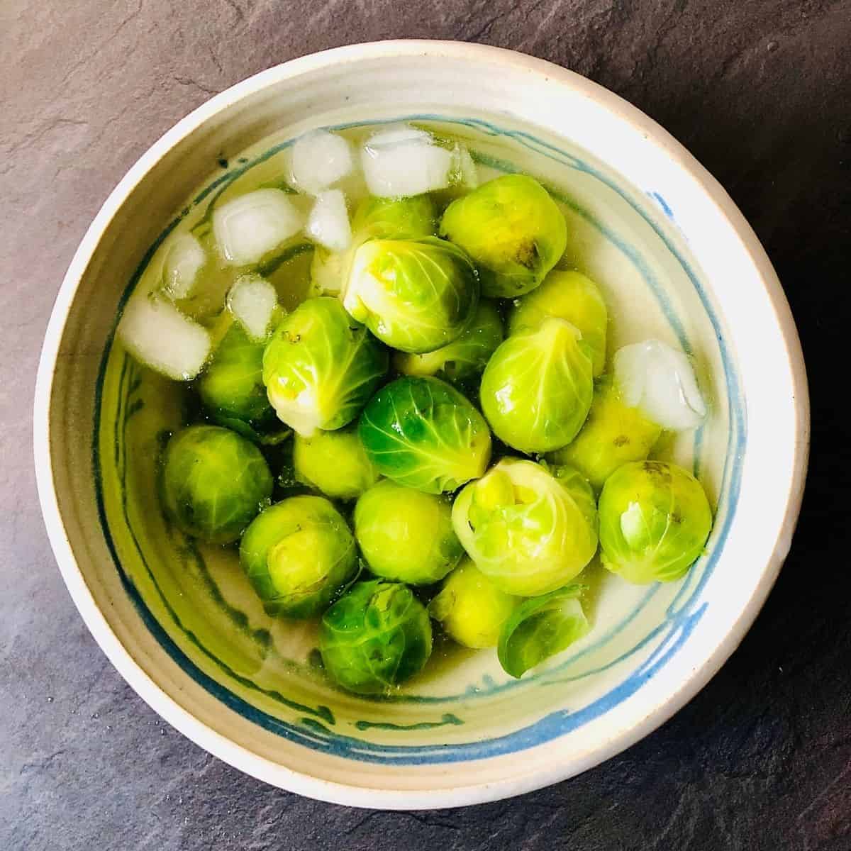 A bowl containing brussel sprouts in iced water
