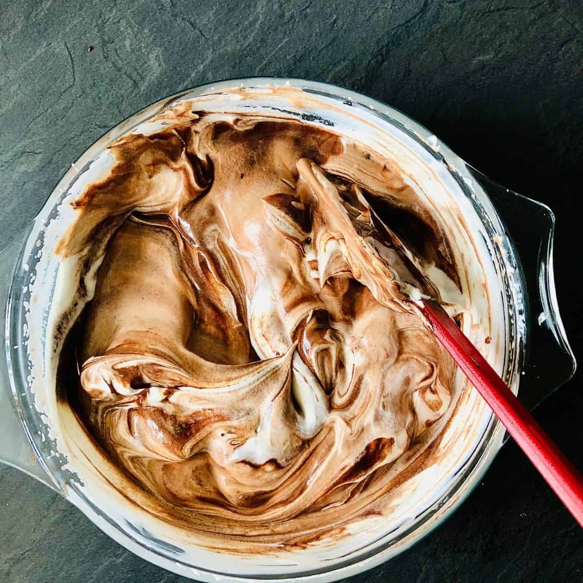 Glass bowl of semi-mixed melted chocolate and whipped cream
