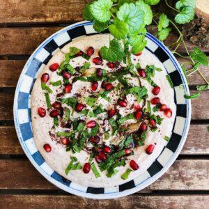 Black eyed pea hummus on a plate garnished with sumac, mint leaves and pomegranate seeds