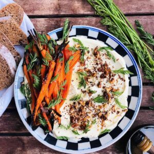 A plate of dairy free labnah garnished with walnut and accompanied by baby carrots