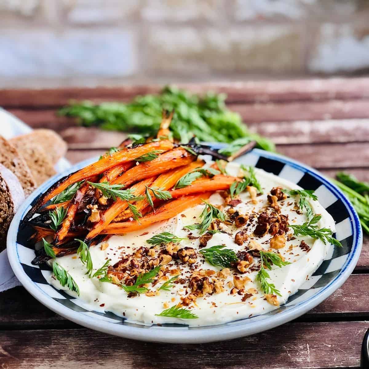 A plate of dairy free labnah garnished with walnut and accompanied by baby carrots