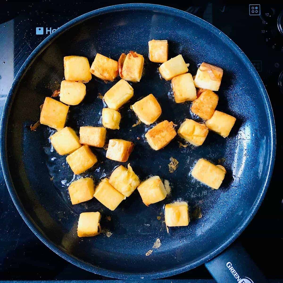 A frying pan containing fried gram flour paneer cubes