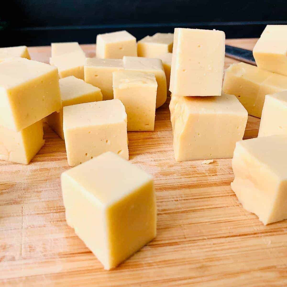 Cubes of gram flour paneer on a chopping board.