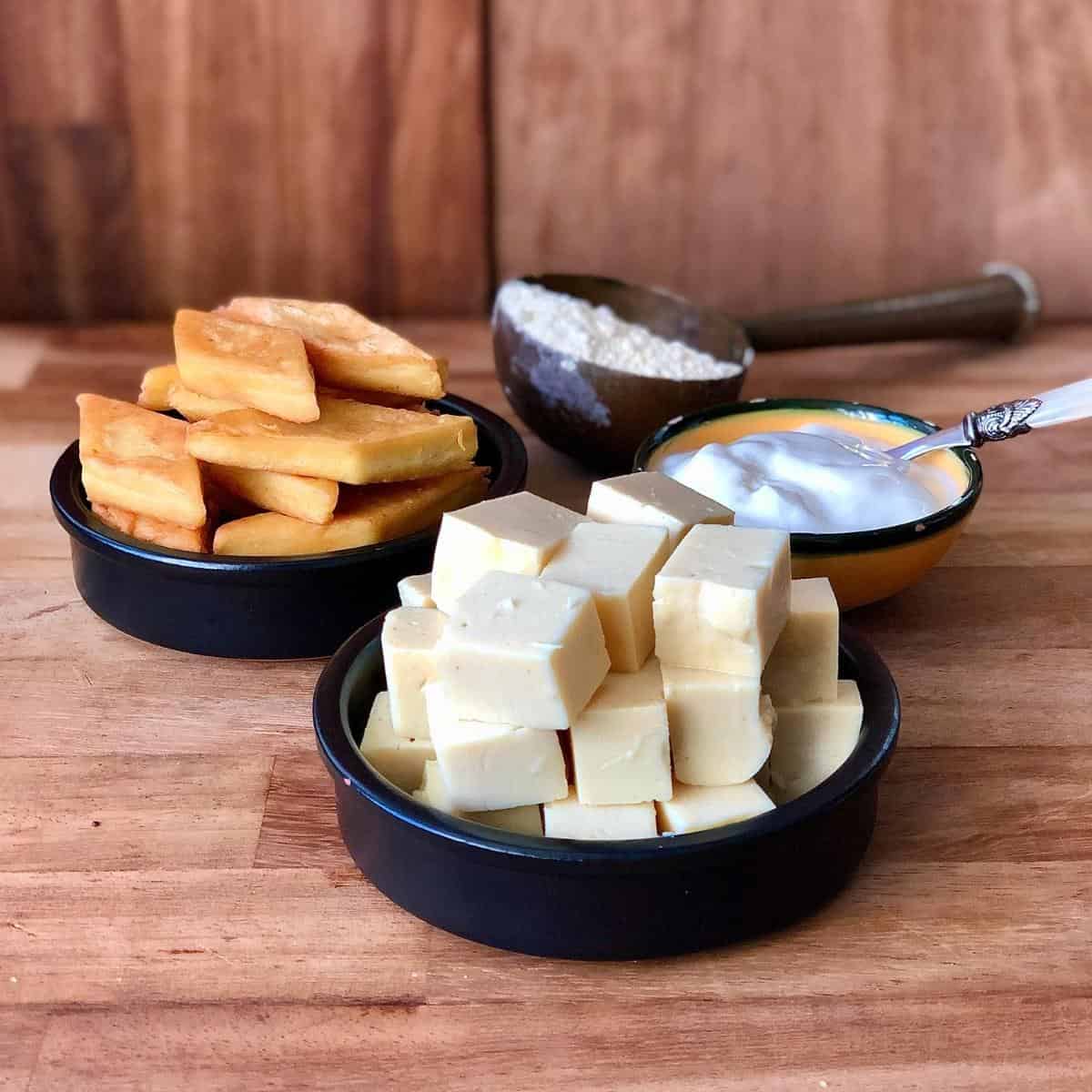 Two shallow dishes containing gram flour paneer. One dish contains fried paneer
