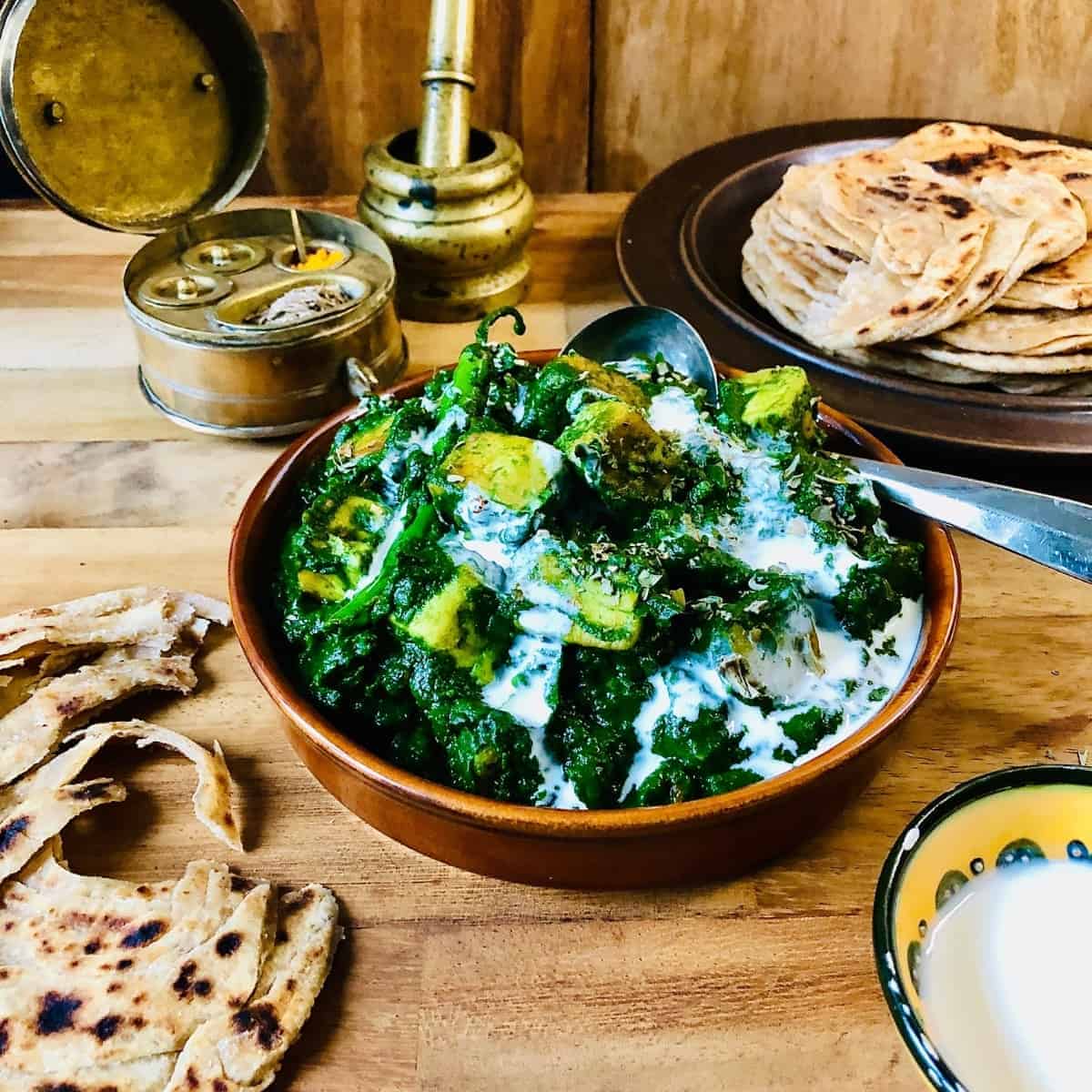 Palak paneer in a shallow dish garnish with vegan cream. 
