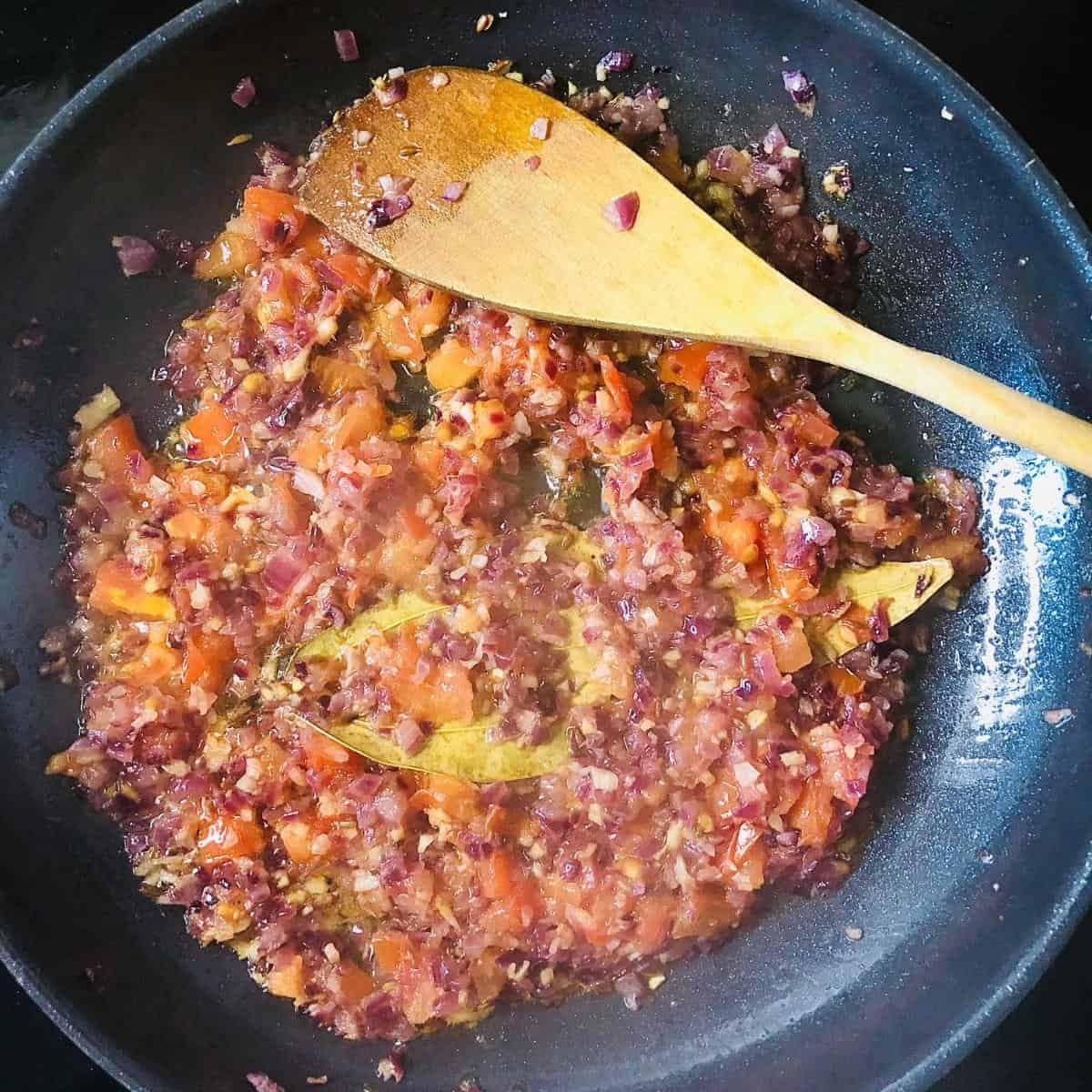 Finely chopped onion, garlic and ginger mixed together and cooking in a frying pan