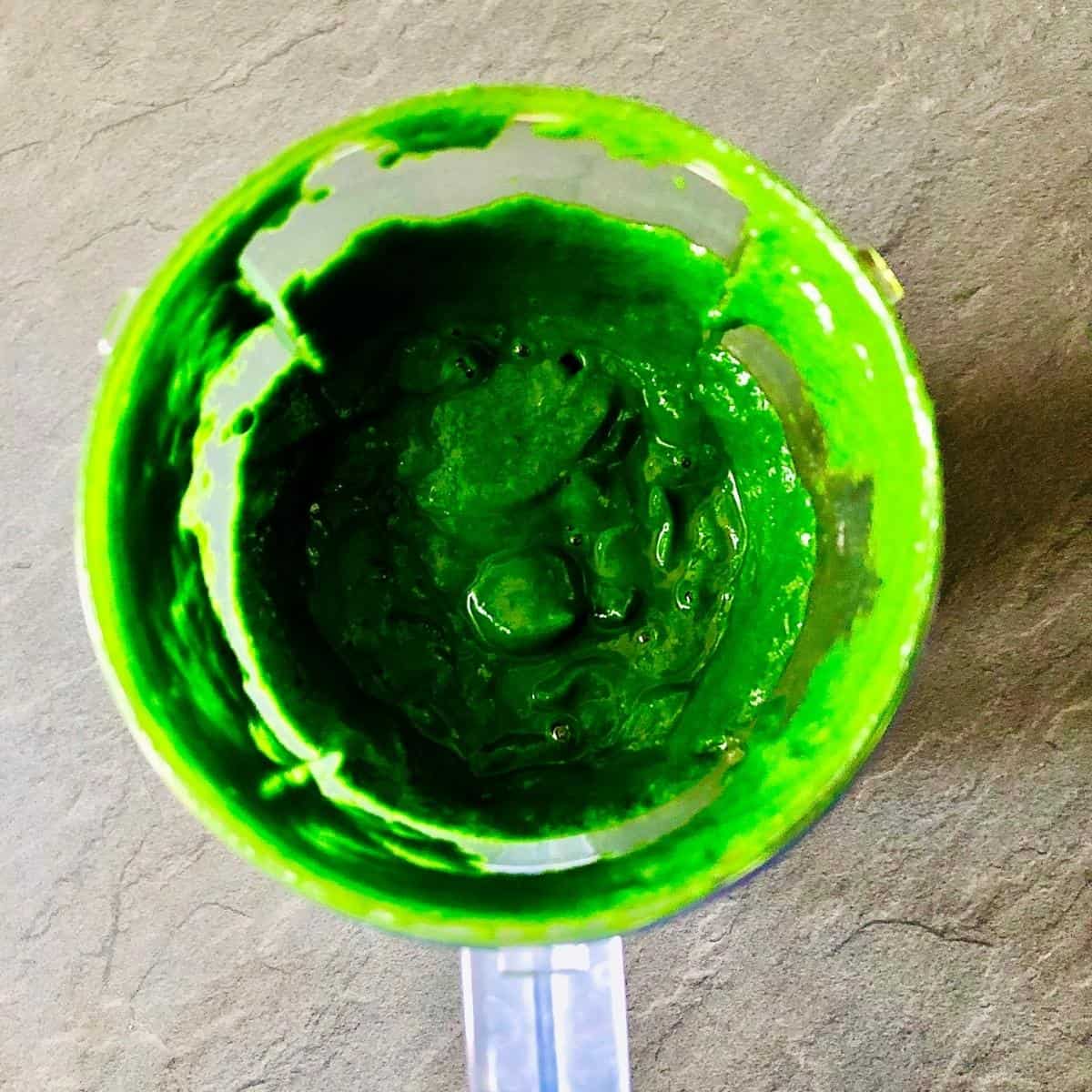 A blender cup containing pureed spinach for palak paneer
