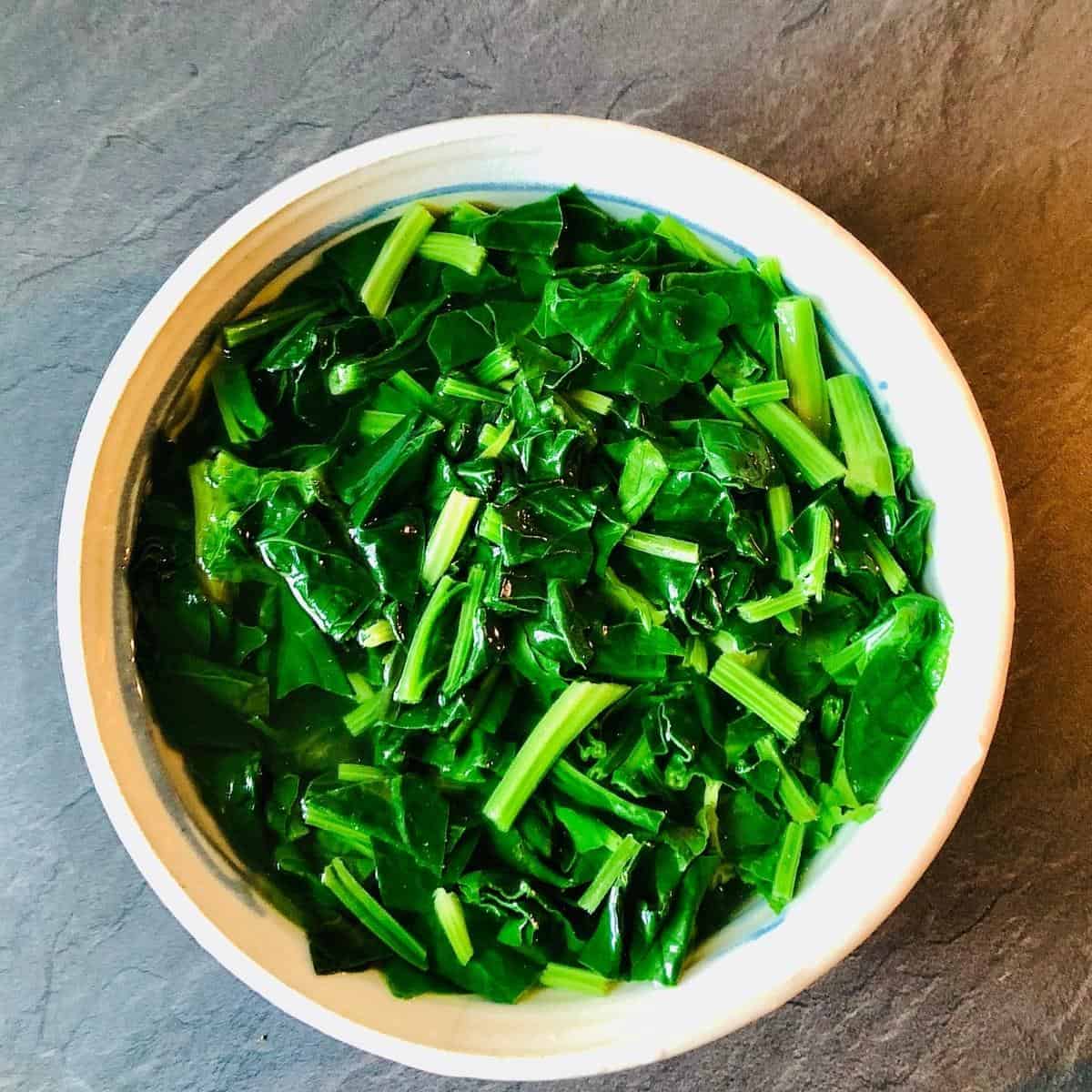 Chopped spinach in ice water bath in a bowl
