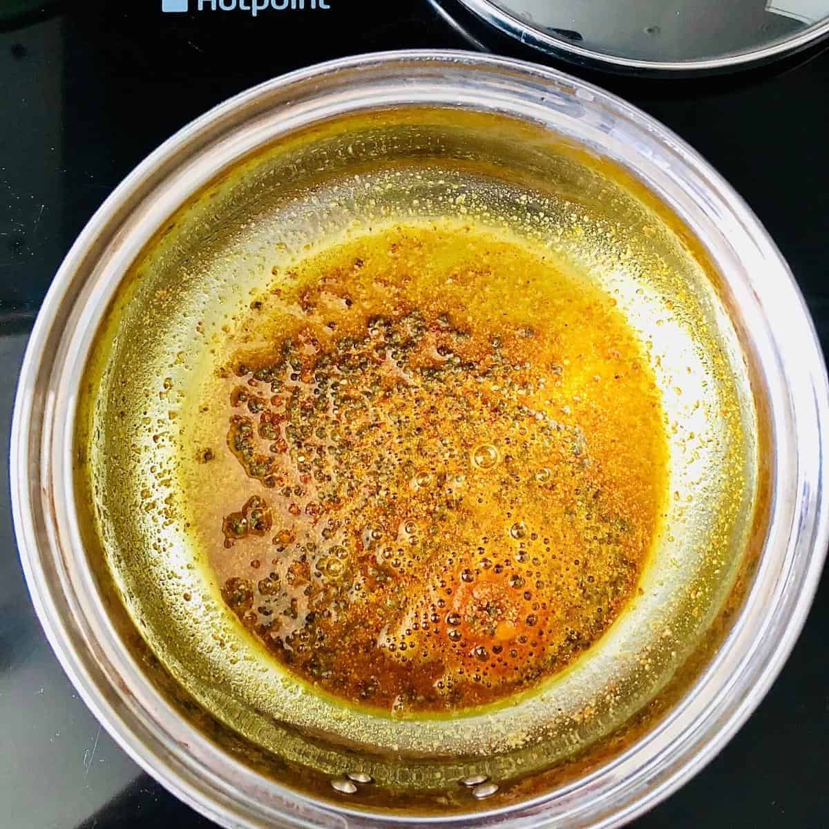 Cooking Mustard seeds and asafoetida in a saucepan