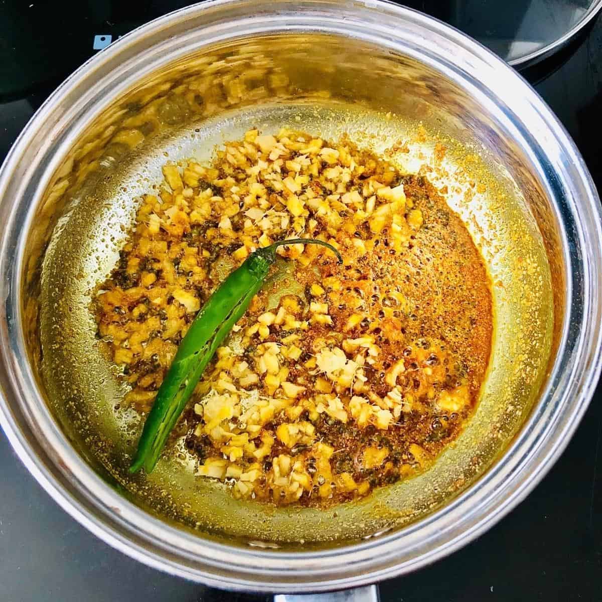 Cooking spices for charchari mixed vegetable recipe in a saucepan