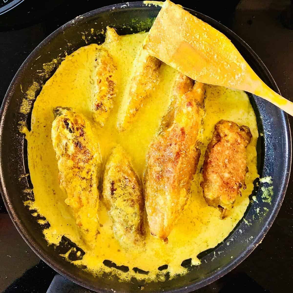 Vegan fish banana blossom cooking in bright yellow mustard sauce