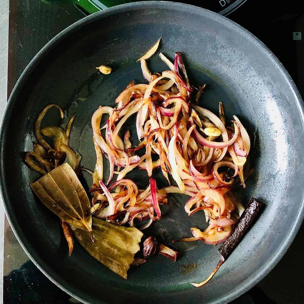 A frying pan containing cooked onion for vegan jackfruit recipe.