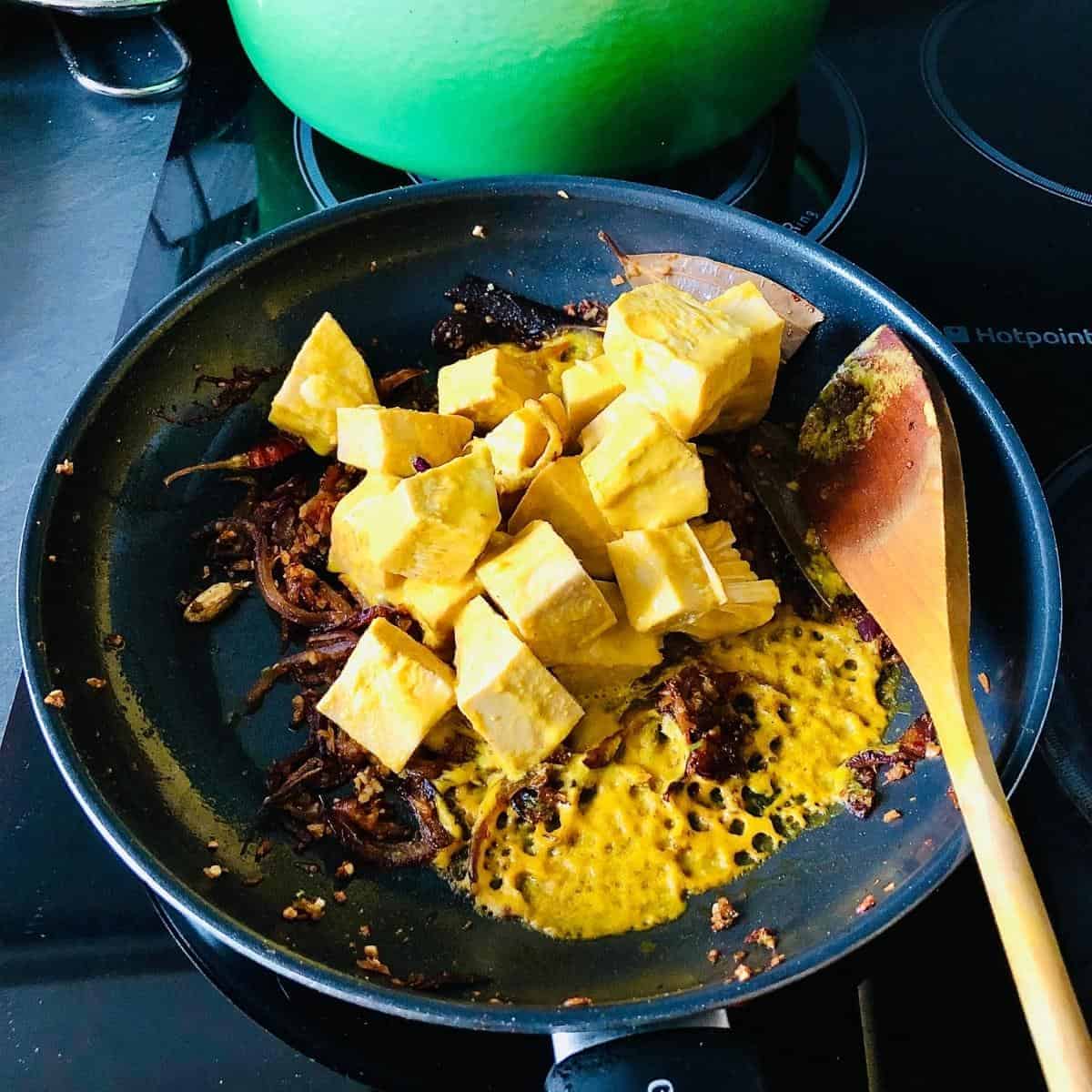 Marinated jackfruit added to cooking base mix for vegan jackfruit recipe in a frying pan