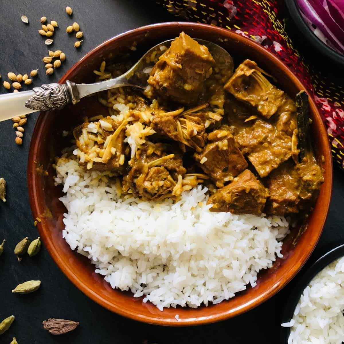 Kosha Mangsho with rice in a shallow dish. 
