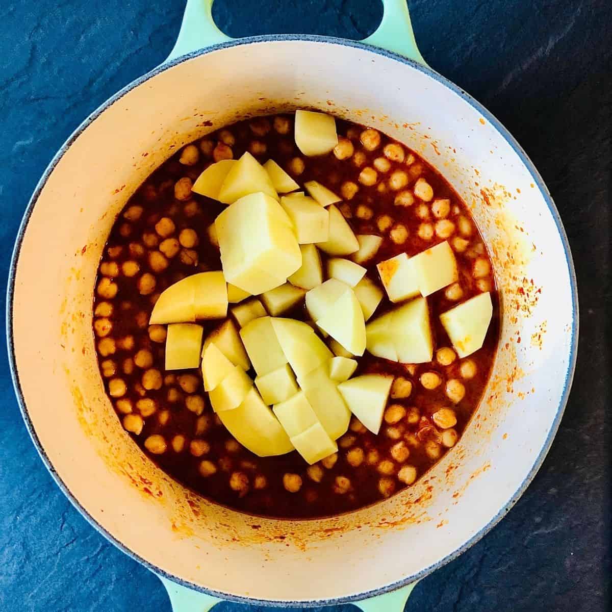 Diced potato added to a pot of thai chickpea curry