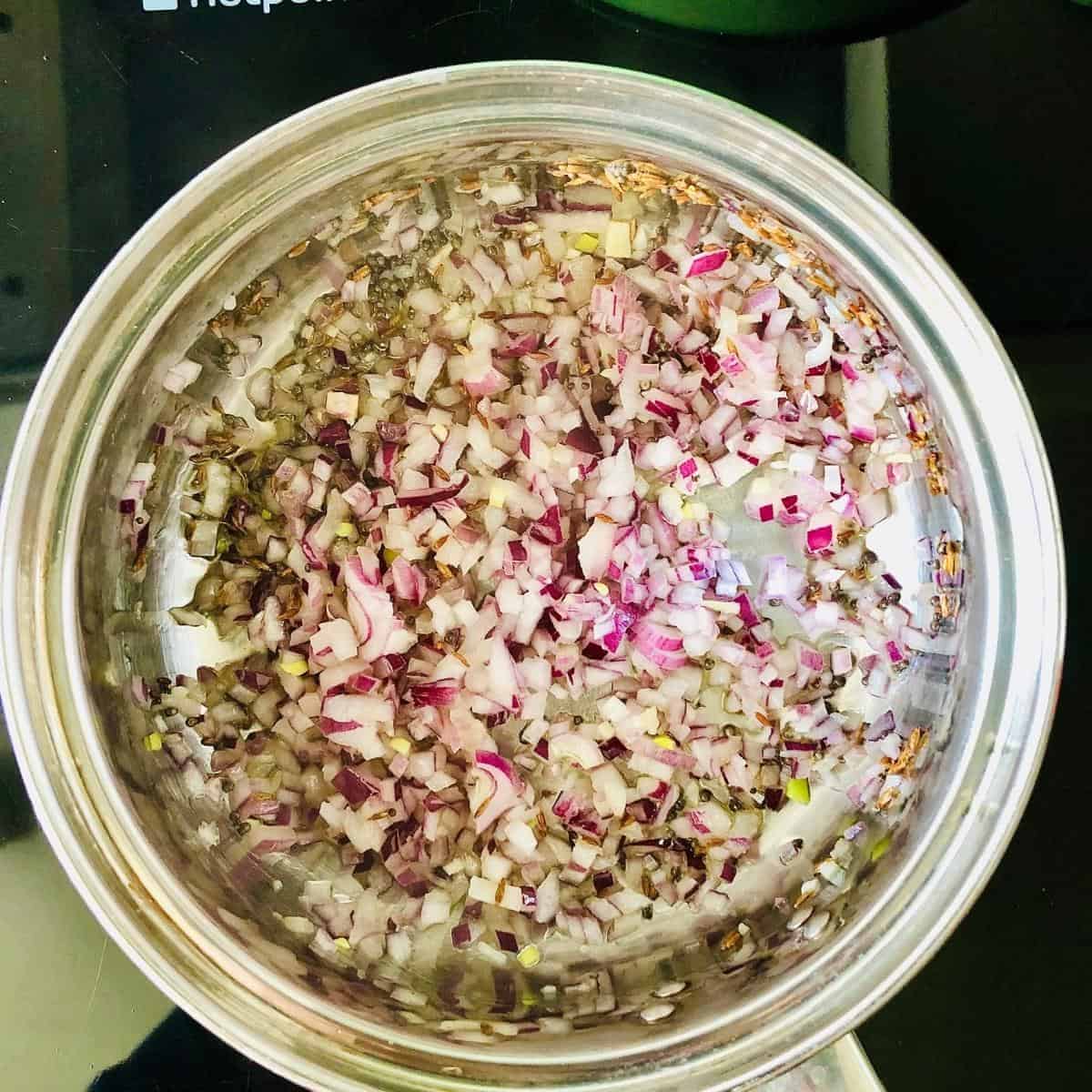 Dalia mix in saucepan with finely chopped red onion added for healthy breakfast recipe