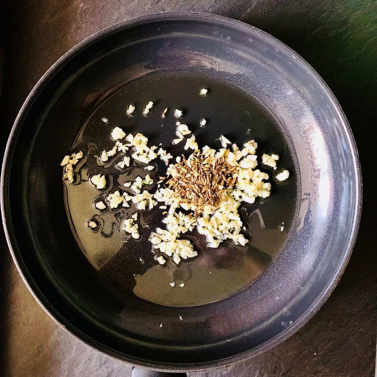 finely chopped garlic and fennel seeds frying in a frying pan