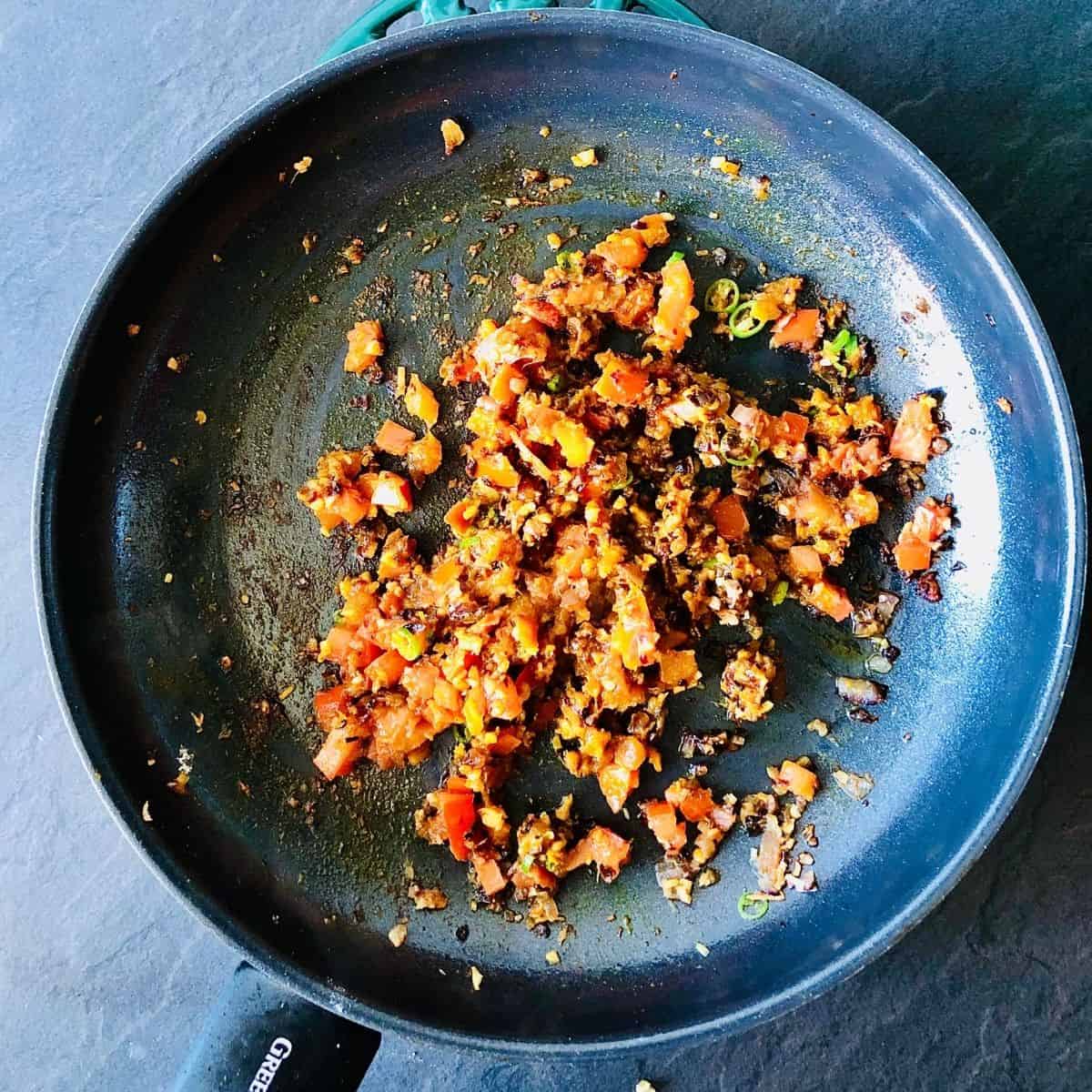 Frying onion, garlic, ginger, green chilli, chopped tomato and spices in a frying pan