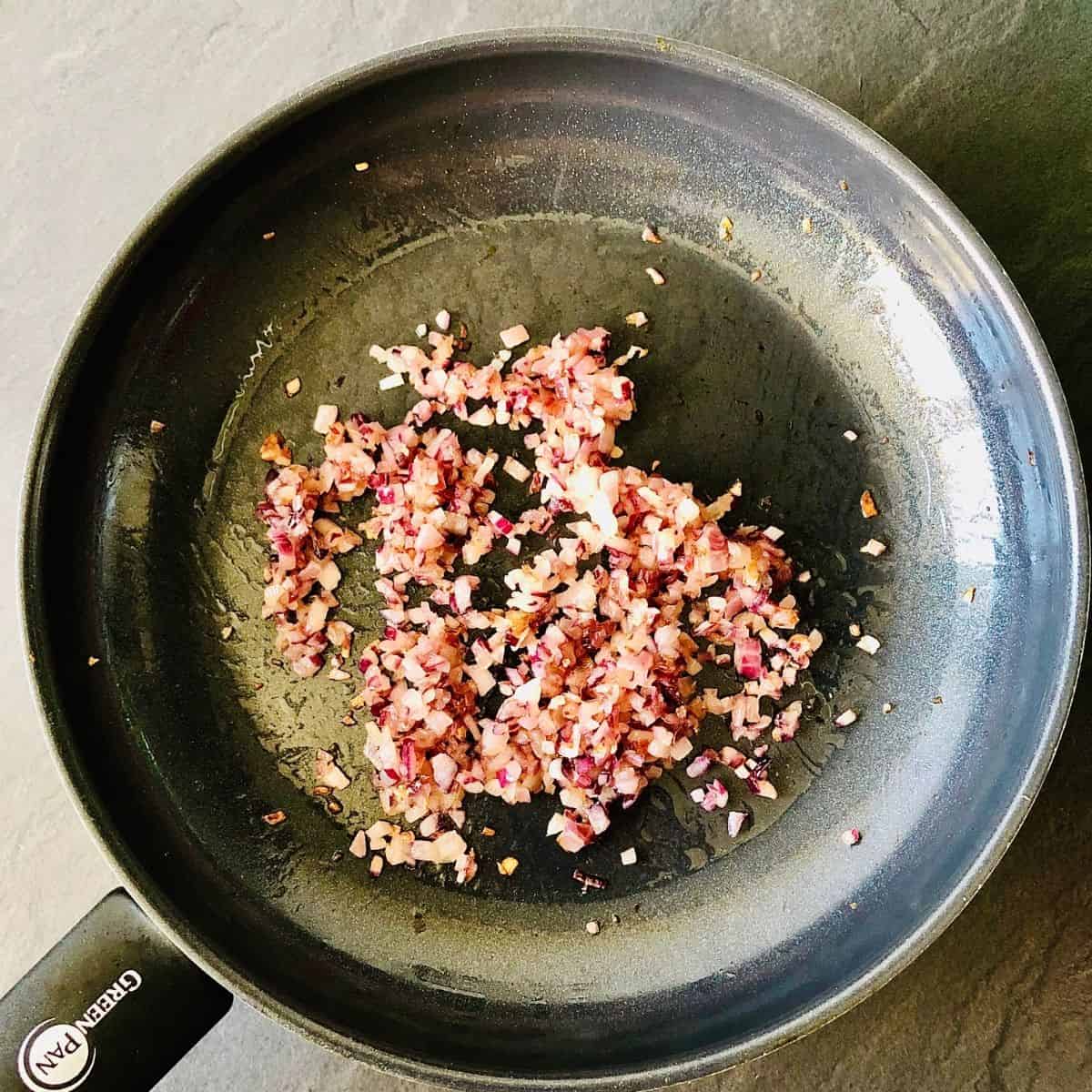 Finely chopped red onion in a pan frying