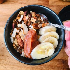 bowl of orange blossom granola with sliced banana and crab apple butter