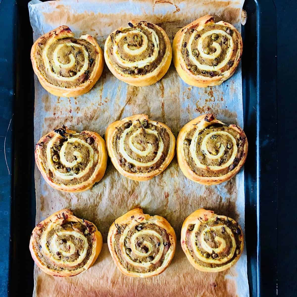 Nine cooked pinwheel samosas on an baking tray lined with parchment paper