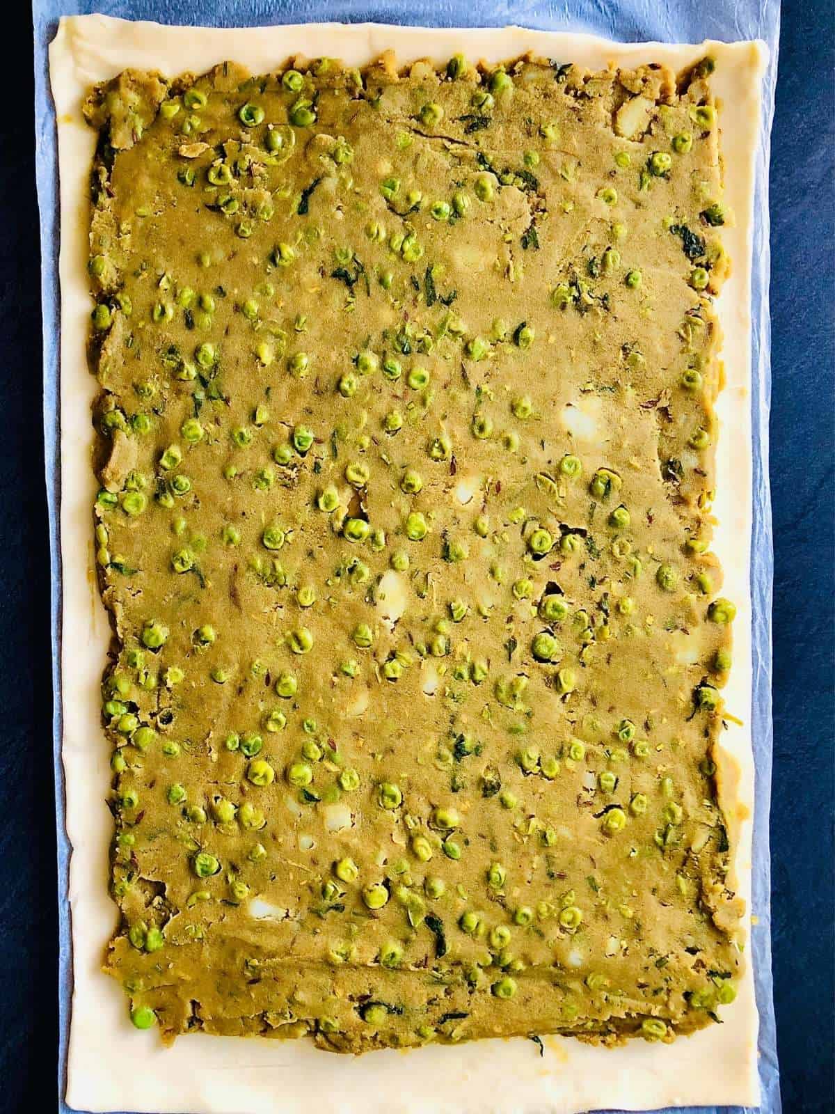 Pinwheel samosa filling spread out onto rectangular shortcrust pastry