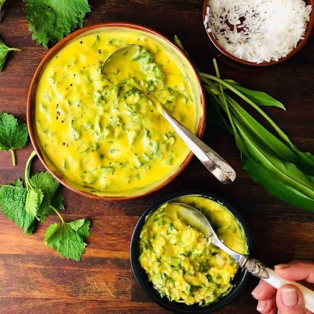 Two shallow dishes. One containing kadhi and the other containing kadhi and rice mixed together