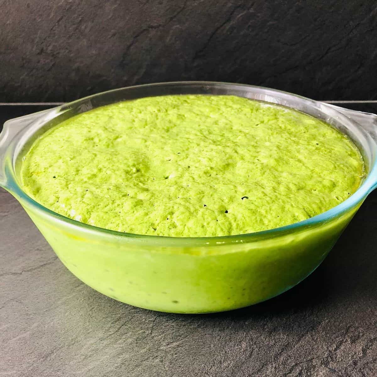 Wild garlic focaccia dough in a glass bowl after proving.