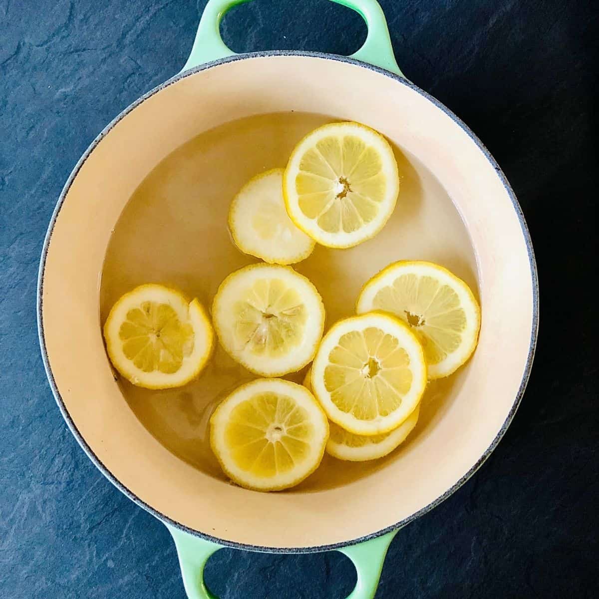 A pot containing sugar solution and lemon slices for elderflower cordial