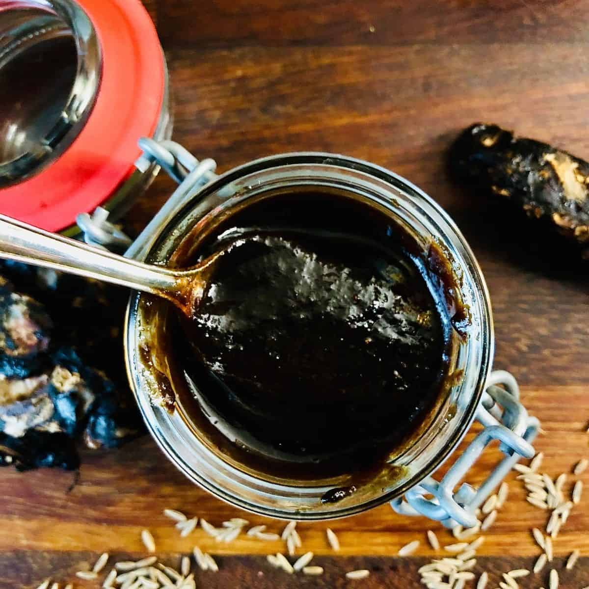 Sonth ki chutney in a small glass jar with a teaspoon.