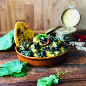 Shallow dish containing saag aloo and a flat bread.